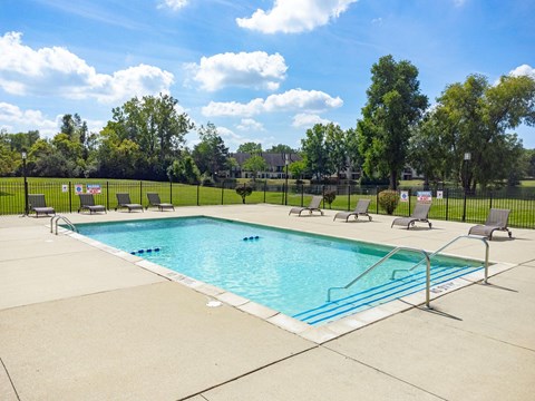 a swimming pool with chairs and a fence around it