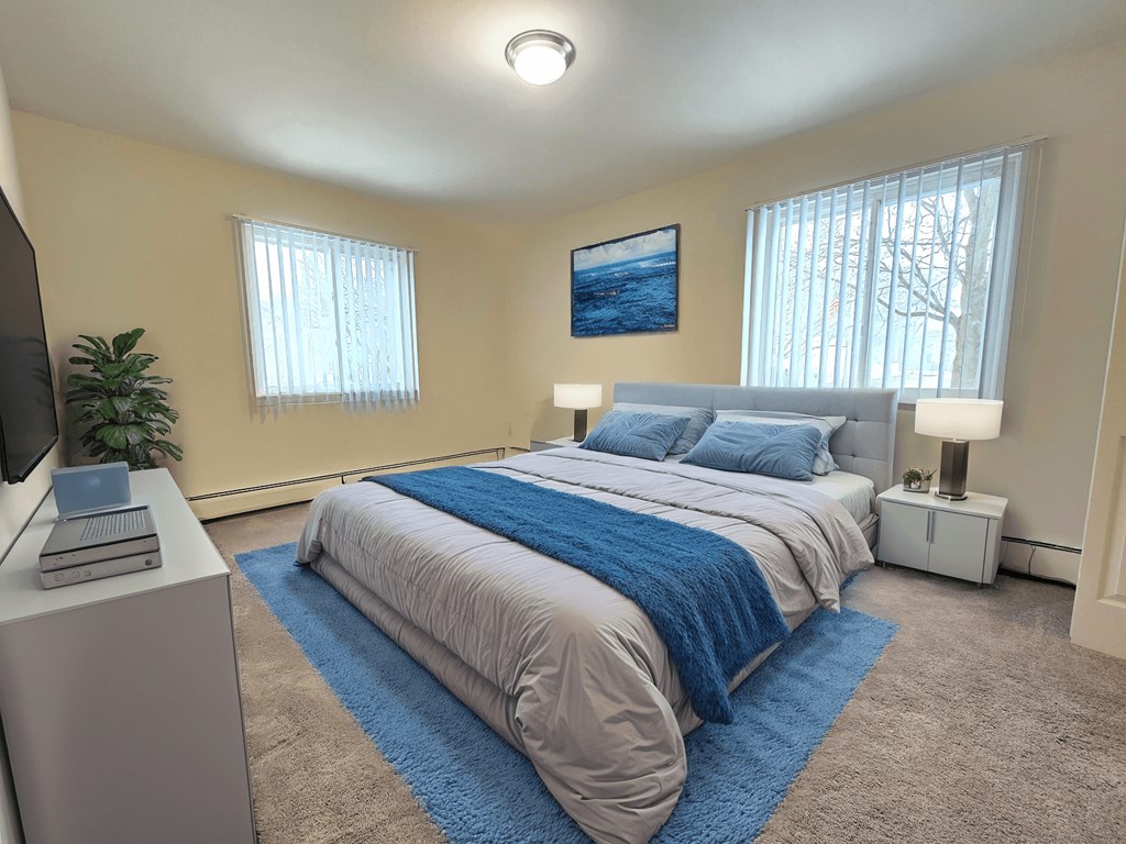 A bedroom with a bed, a television, and a painting on the wall.