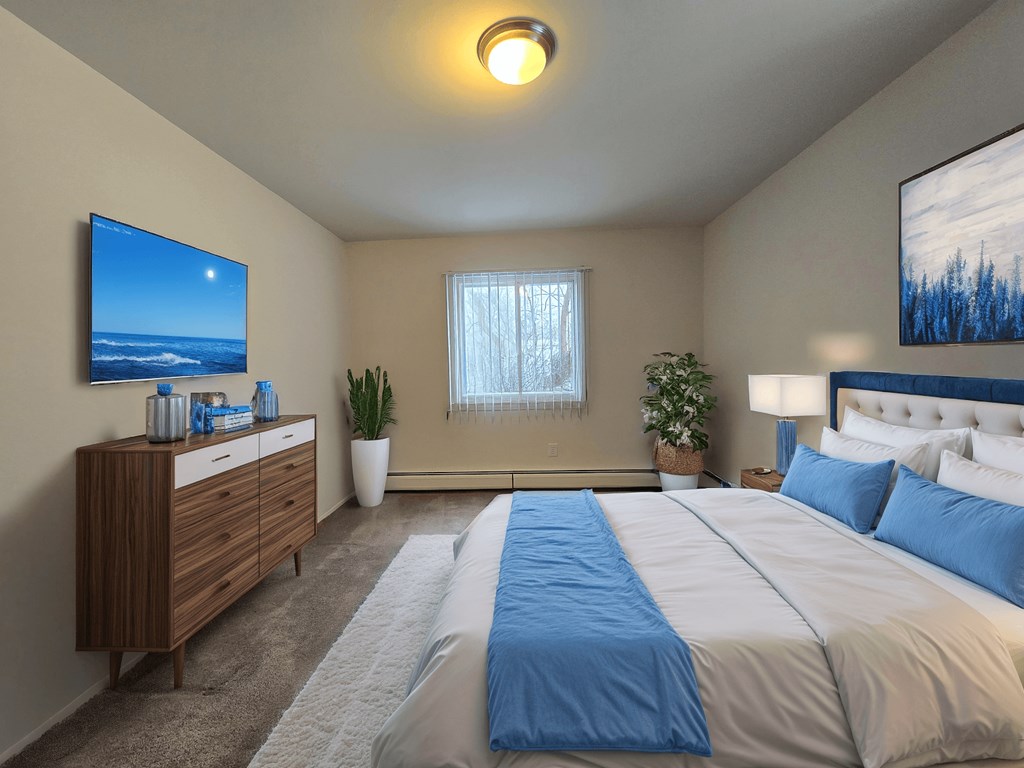 A bedroom with a large bed and a flat screen TV mounted on the wall.