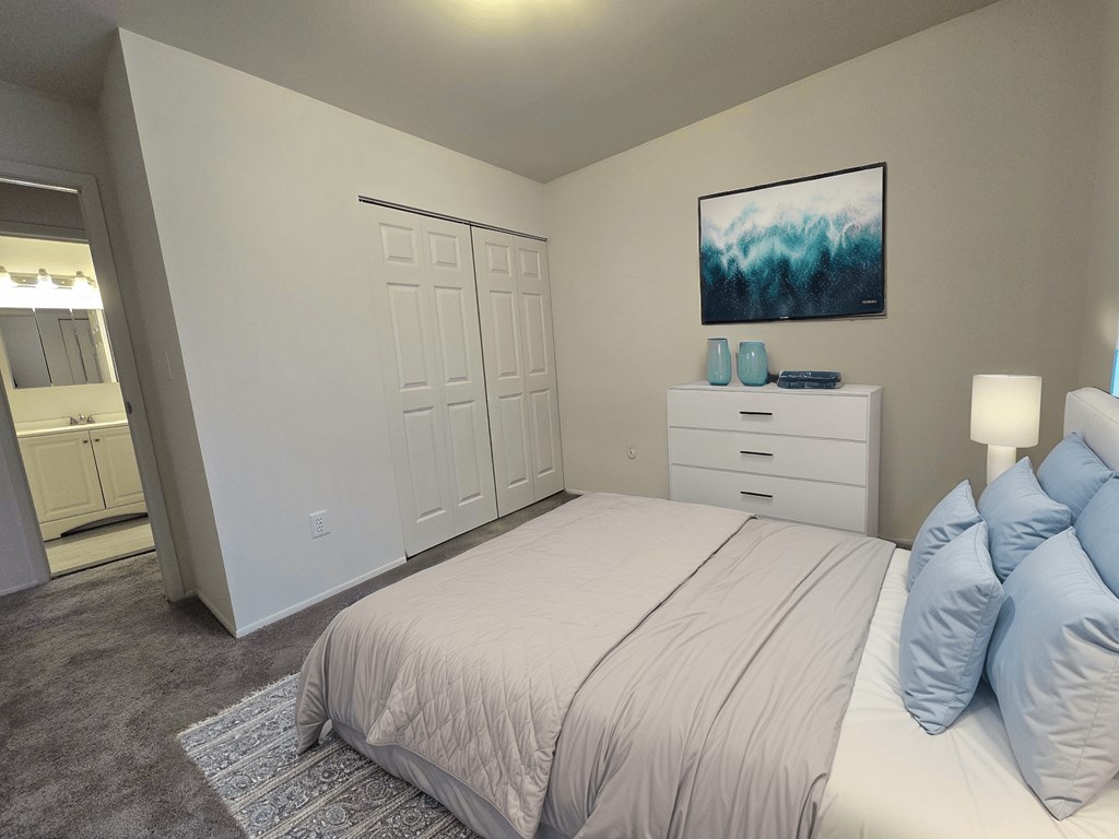A bedroom with a bed, dresser, and a painting on the wall.