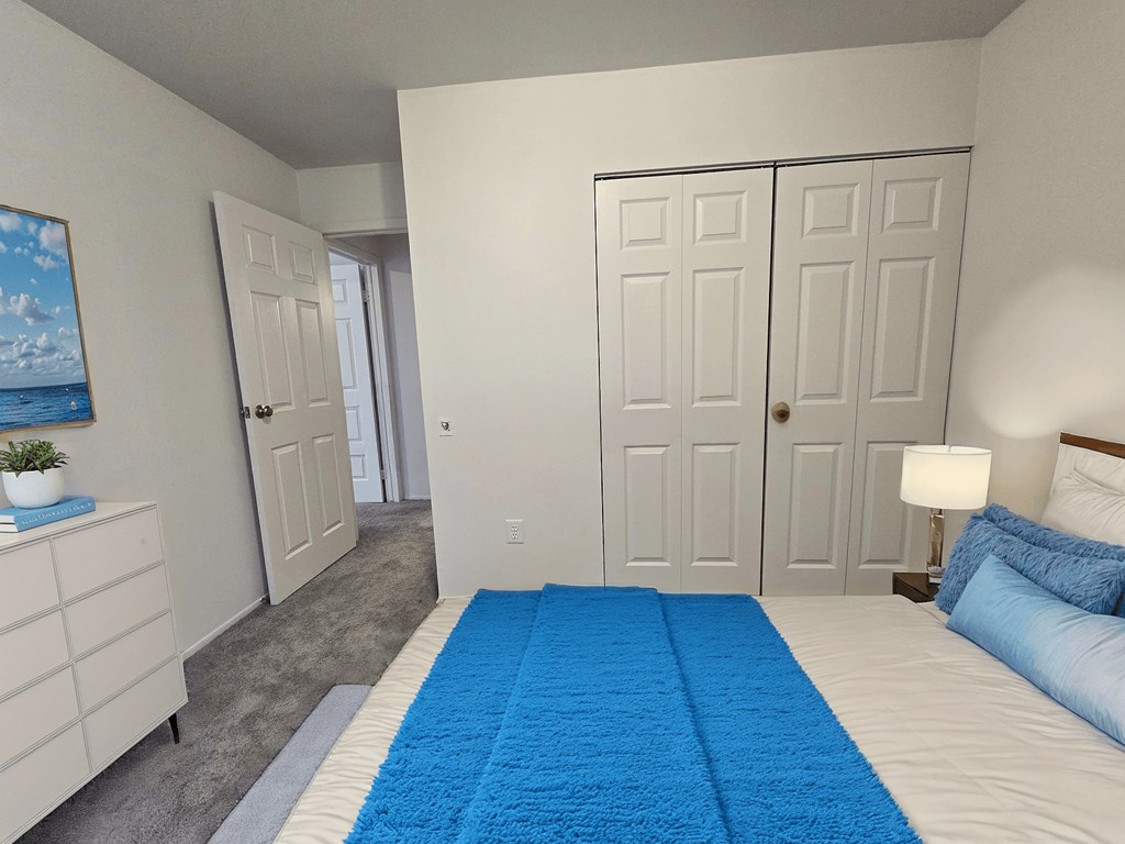 A bedroom with a blue rug and a bed with blue pillows.