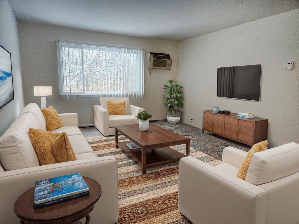 A living room with a white couch, a brown coffee table, and a flat screen TV mounted on the wall.