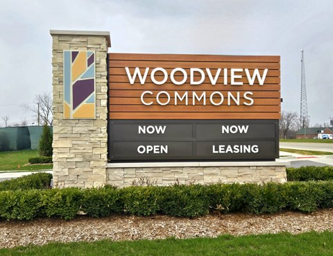 A sign for Woodview Commons shows that it is now open and leasing.