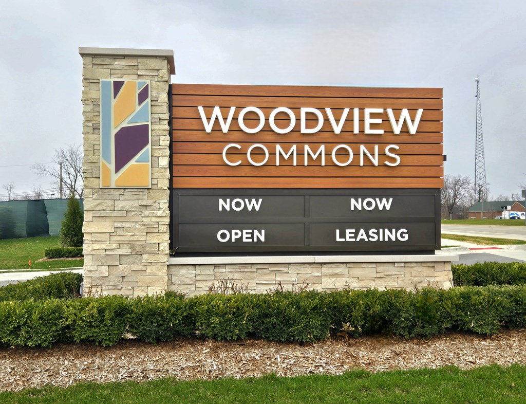 A sign for Woodview Commons shows that it is now open and leasing.