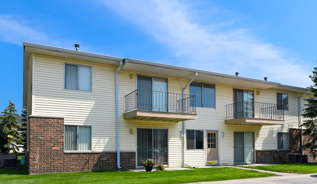 A two-story apartment building with a balcony on the second floor.