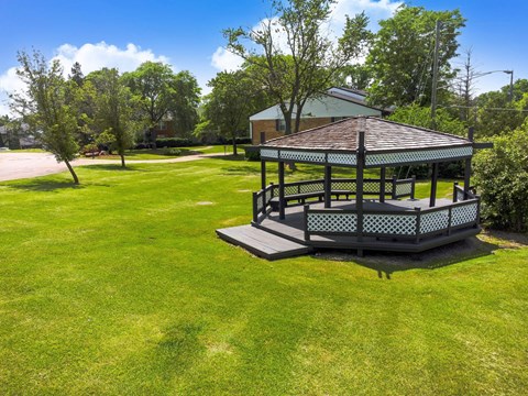 a gazebo in the middle of a grassy area with a house
