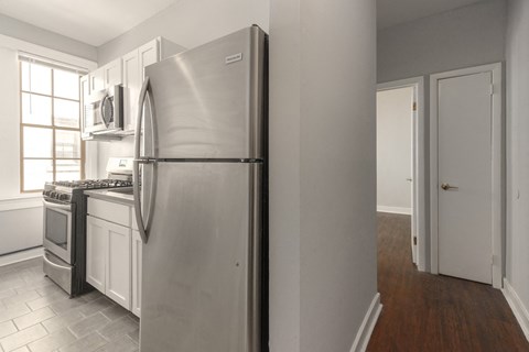 A kitchen with a stainless steel refrigerator and a microwave above the stove.