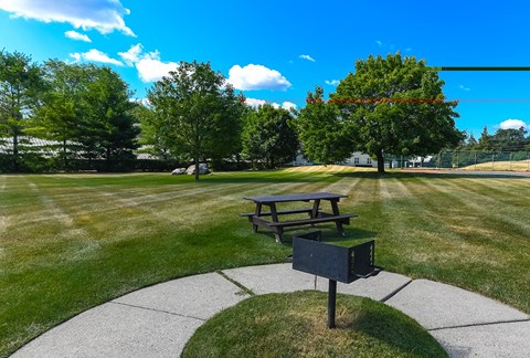 A picnic table sits in the middle of a grassy field.