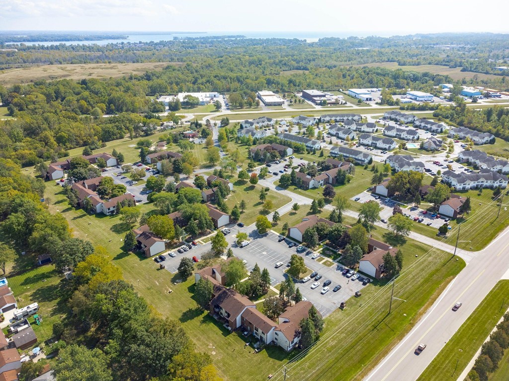 A bird's eye view of a residential area with houses, trees, and a road.
