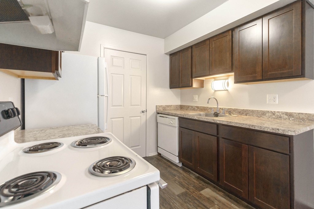a kitchen with white appliances and brown cabinets and a white door