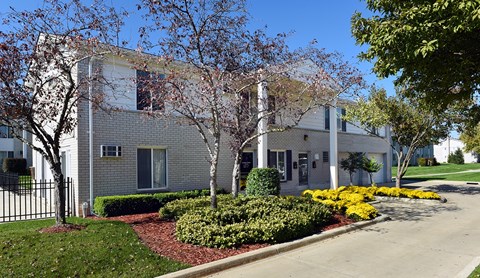 A white building with a black fence and trees in front.