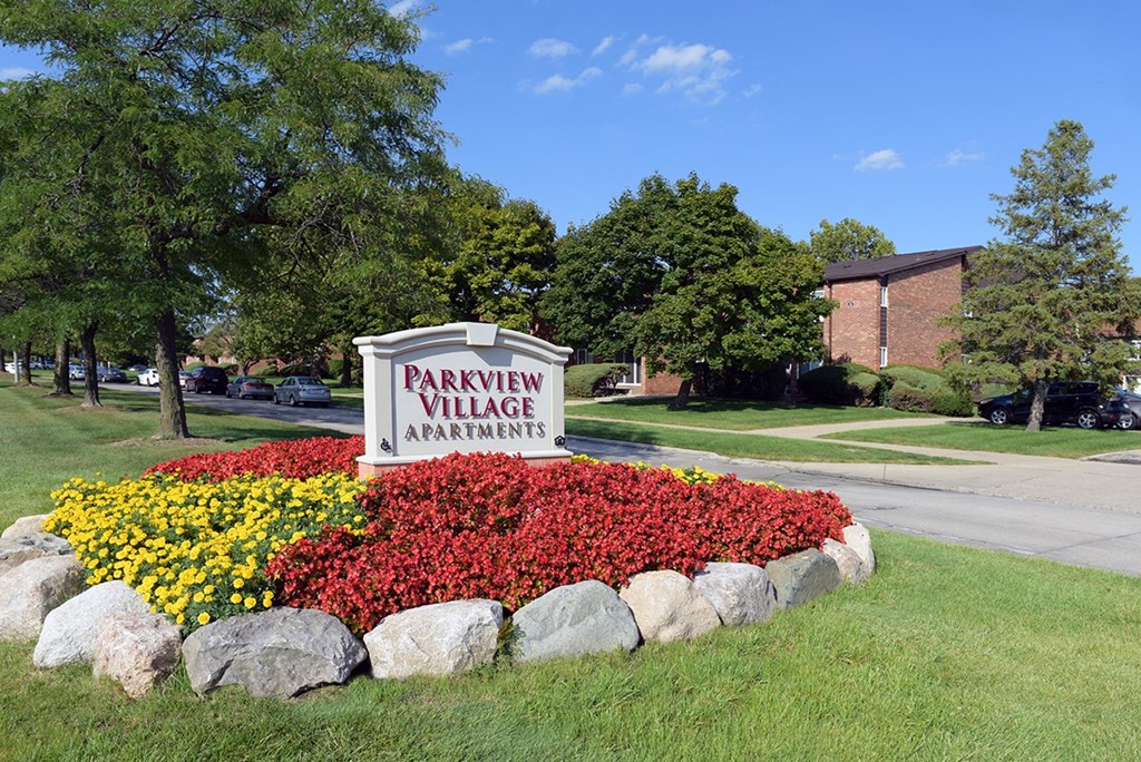 A sign for Parkview Village Apartments is surrounded by a flower bed.