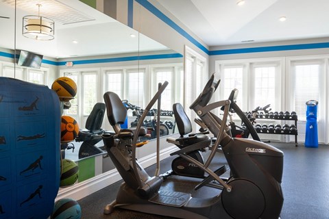a gym with treadmills and other exercise equipment in a room with windows