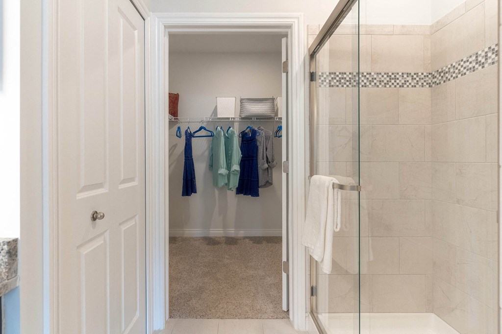 a bathroom with a shower and a closet with robes and towels
