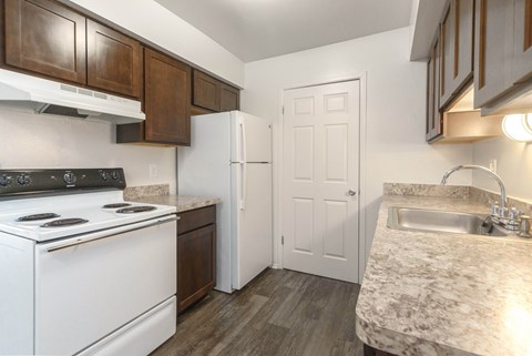 A kitchen with a white stove top oven and a white refrigerator.