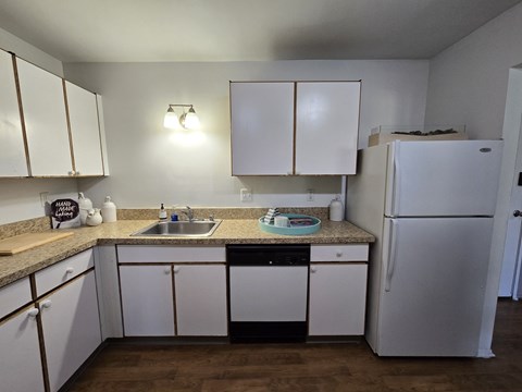 A kitchen with white cabinets and a white fridge.
