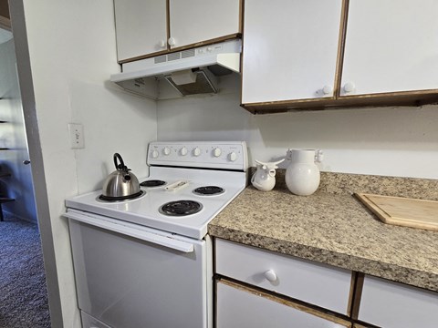 a kitchen with a stove and a counter with a kettle on it