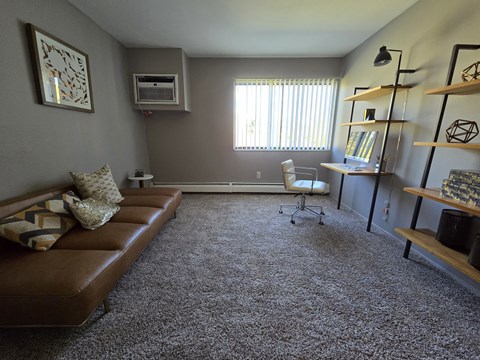a living room with a couch and a desk and a window