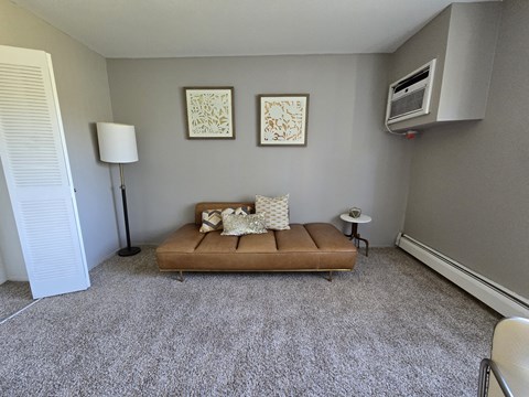 A living room with a brown couch and two framed pictures on the wall.