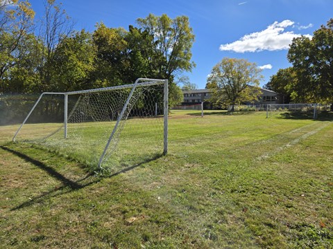 a soccer goal on a field with a house in the background