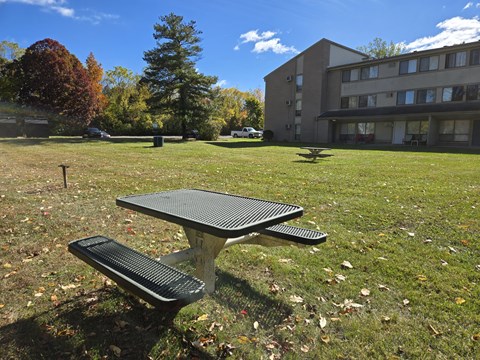 a picnic table in the grass in front of a building