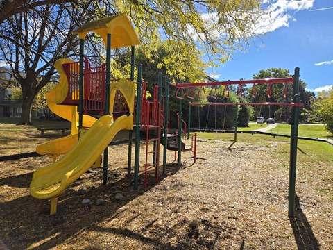 a playground with a yellow slide and a red swing set