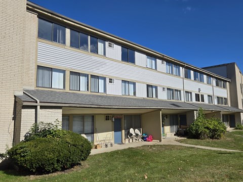 a view of the side of a brick apartment building with a porch and grass