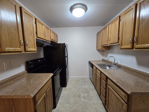 A kitchen with wooden cabinets and black appliances.