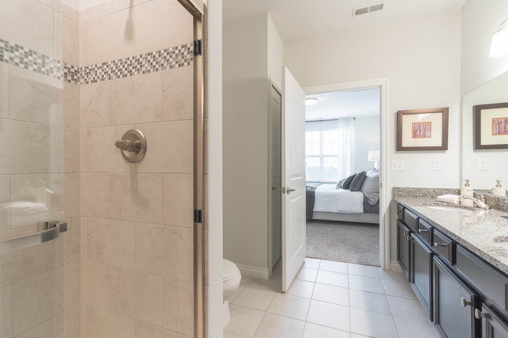 a bathroom with a shower and a sink and a bedroom