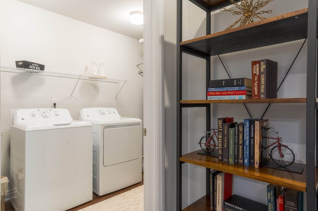 a laundry room with a washer and dryer and a book shelf with books