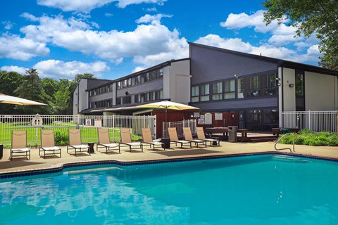 A swimming pool in front of a building with sun loungers.