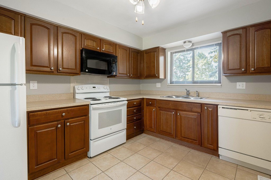 A kitchen with brown cabinets and white appliances.