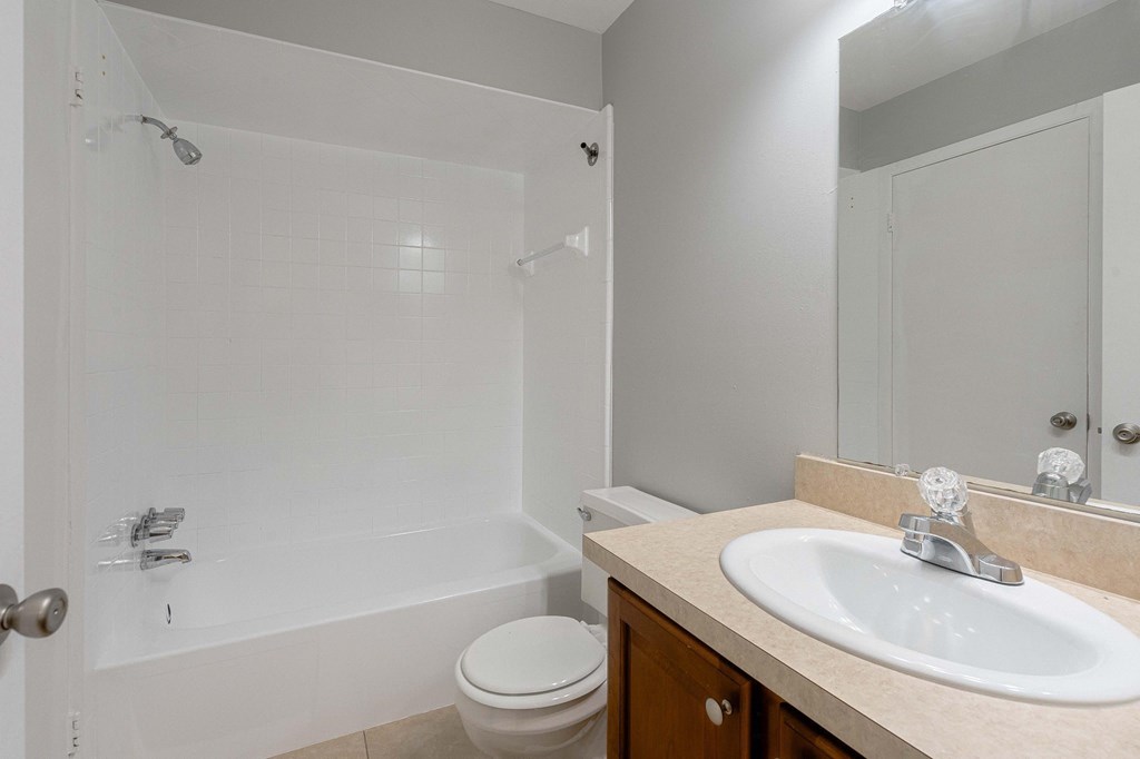 A white bathroom with a toilet, sink, and shower.