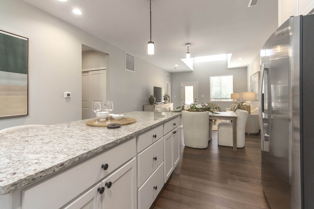 a kitchen with white cabinets and a marble counter top