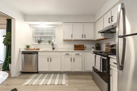 a white kitchen with stainless steel appliances and white cabinets