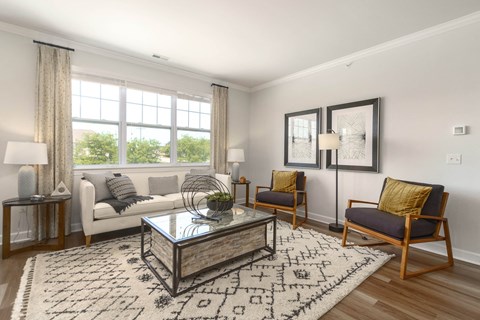A living room with a white couch, a glass coffee table, and a rug with letters on it.