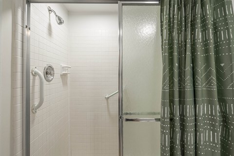 a shower with a green shower curtain in a bathroom