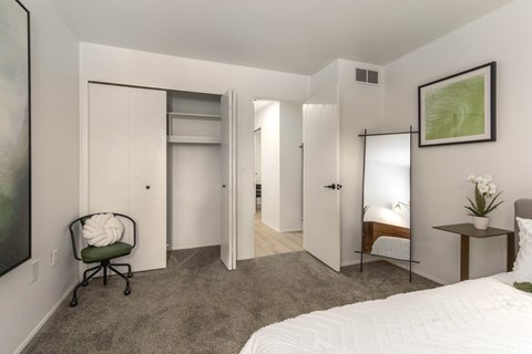 a bedroom with a white bed and a closet with mirrored doors