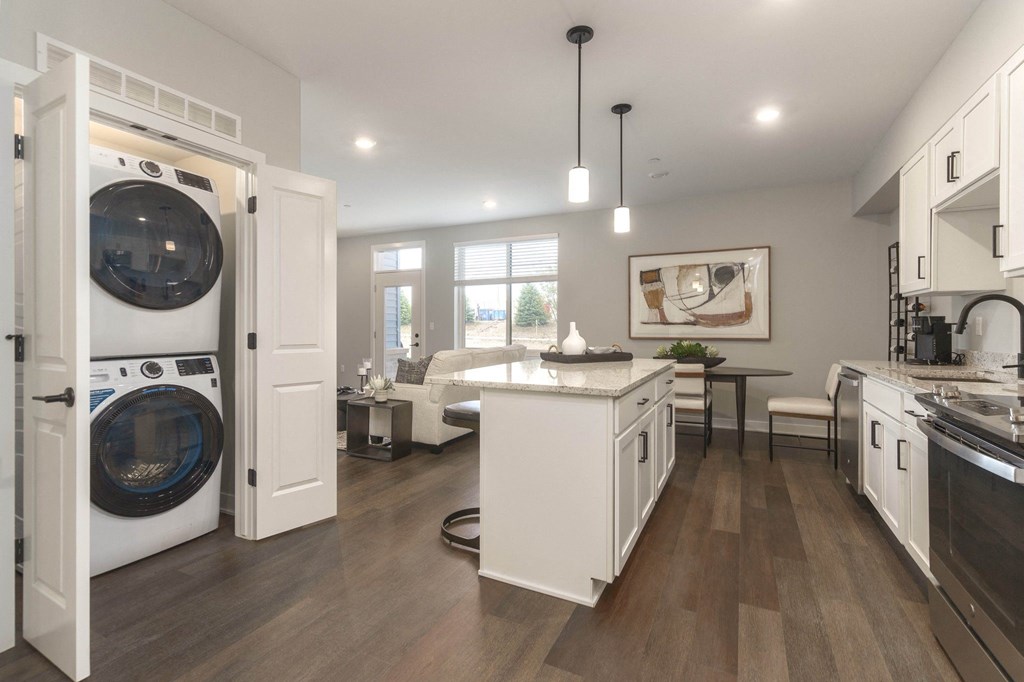 a kitchen with a washer and dryer and a living room with a couch