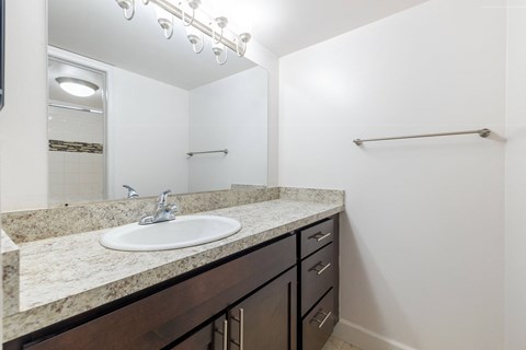 A bathroom with a sink, mirror, and a towel bar.