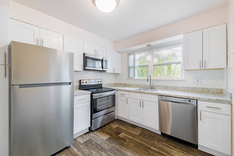 A kitchen with a stainless steel refrigerator, microwave, oven, and dishwasher.