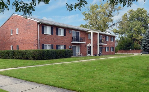A red brick building with a green lawn in front.