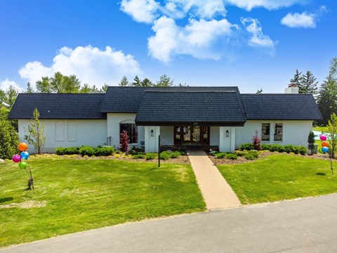 the front of a white house with a green lawn and
