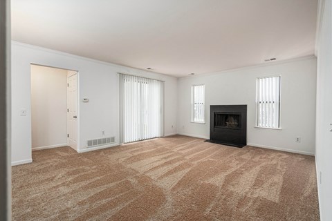 an empty living room with a fireplace and white walls