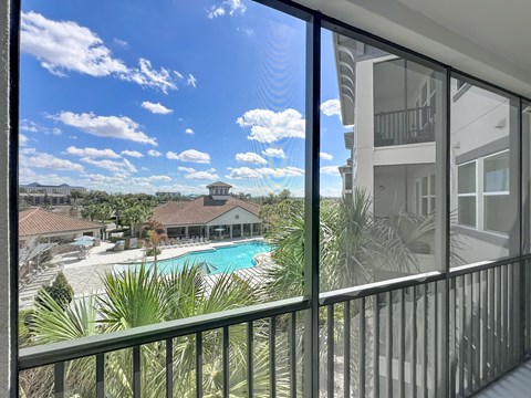A view from a balcony looking out at a pool and a building.