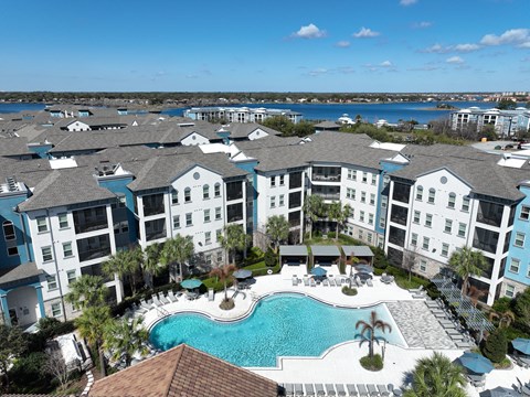 A large apartment complex with a swimming pool in the foreground.