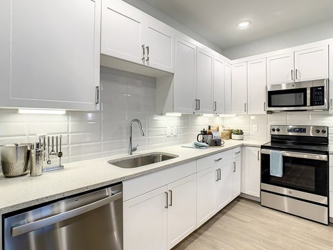 A modern kitchen with white cabinets and stainless steel appliances.