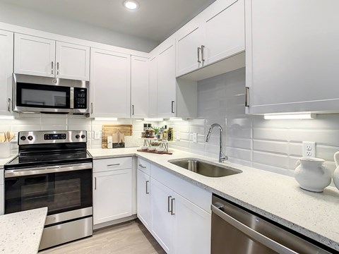 A modern kitchen with white cabinets and stainless steel appliances.