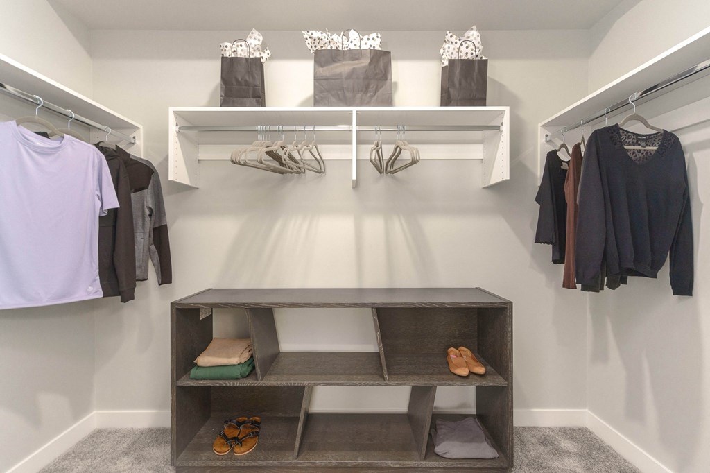 a walk in closet with shelves and clothing racks