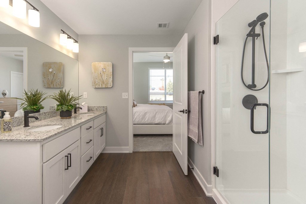 a bathroom with white cabinets and a shower and a bed